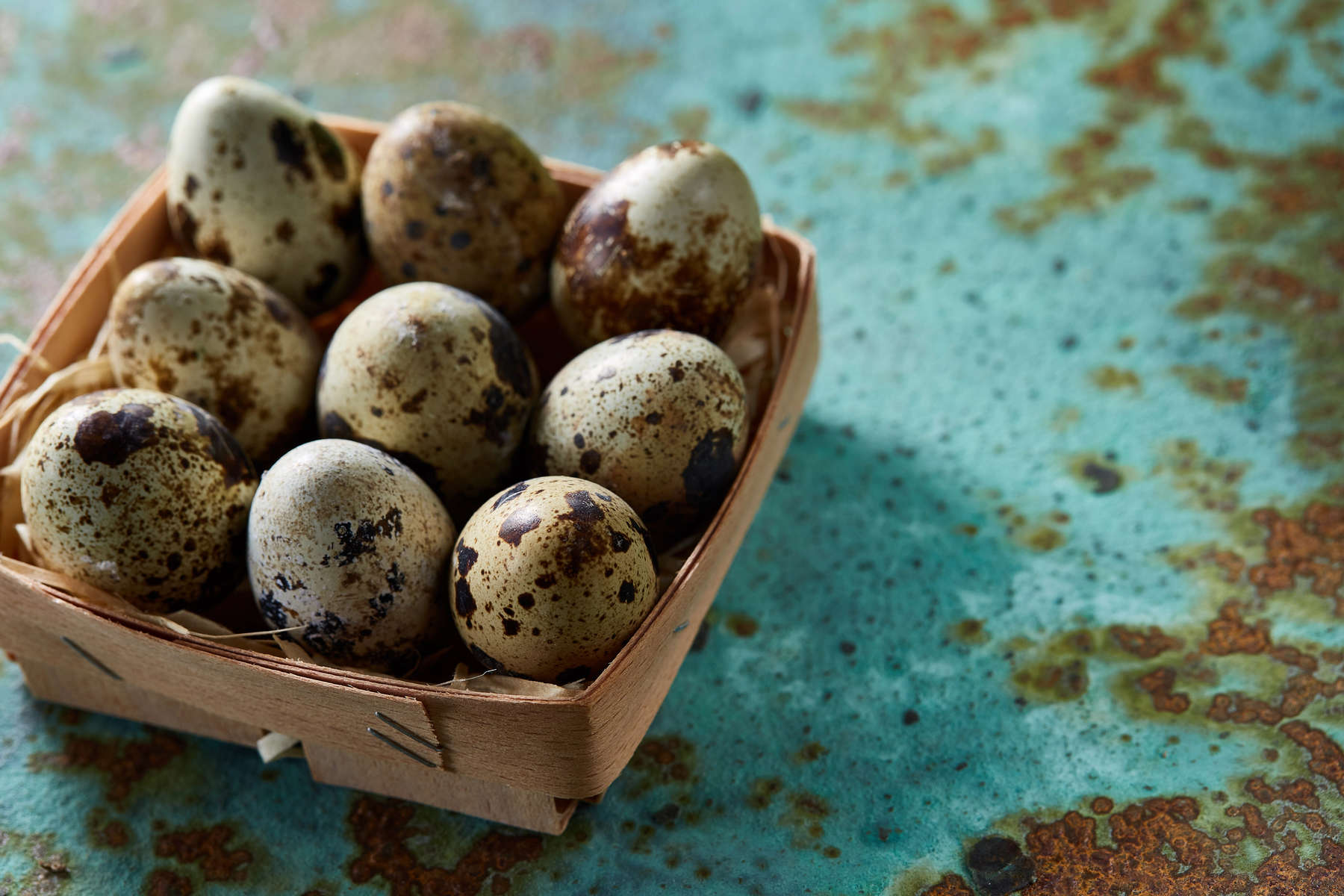 Quail eggs in a box on a blue textured background, top view, selective focus.