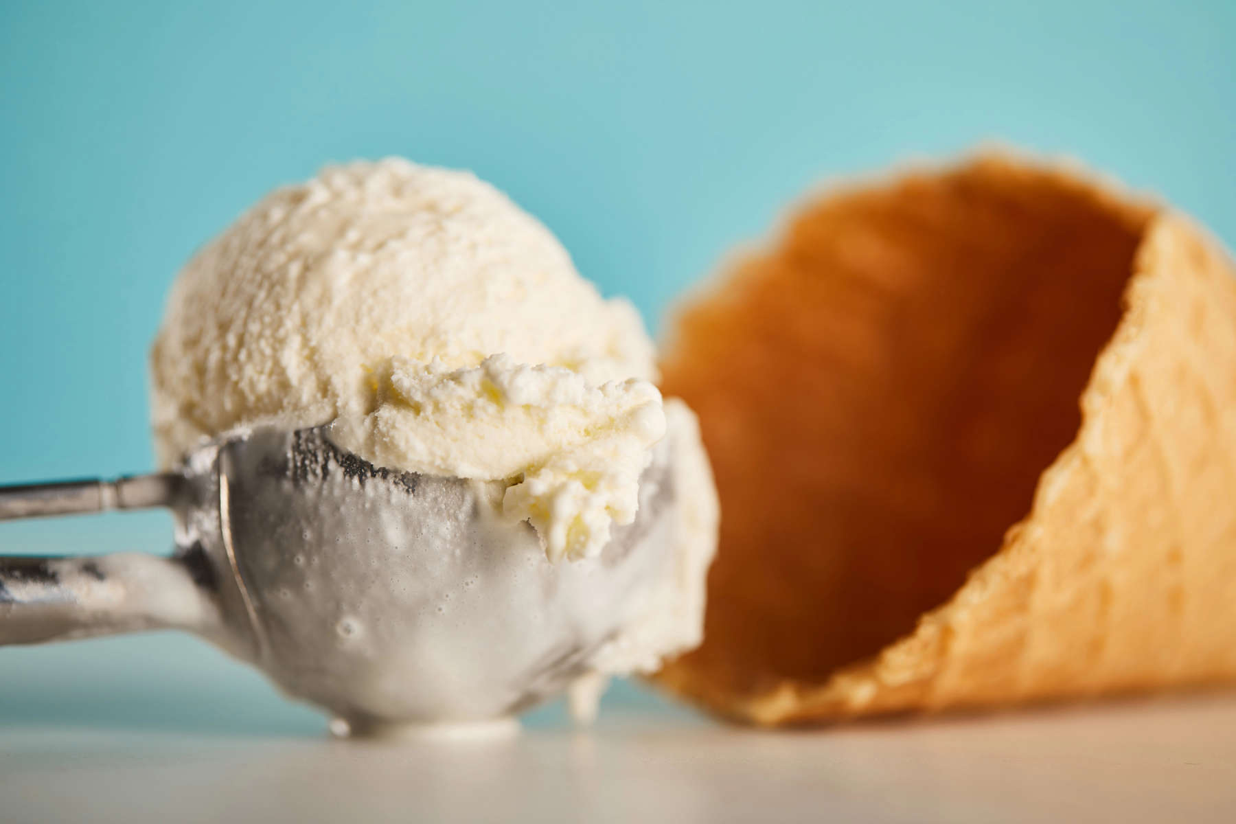 delicious ice cream scoop in spoon and waffle cone on blue